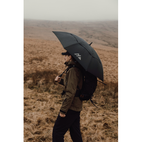 Personne avec sac à dos tenant un parapluie ouvert en extérieur, sans marquage visible