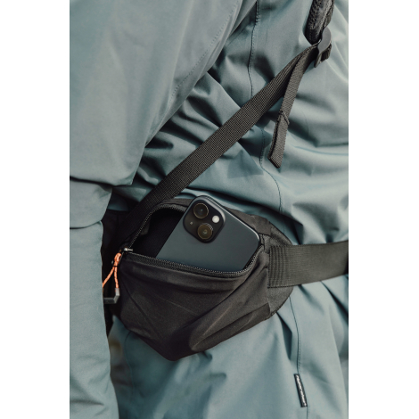 Gros plan sur poche zippée portée à la taille contenant un objet, sans marquage visible