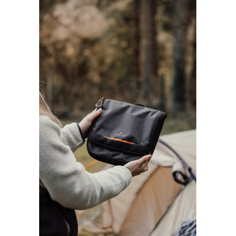 Personne tenant une trousse fermée en extérieur, sans marquage apparent