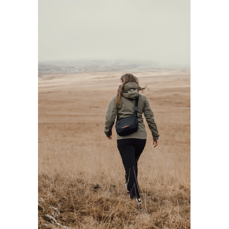 Personne marchant en extérieur avec sac porté en bandoulière dans le dos, sans marquage visible