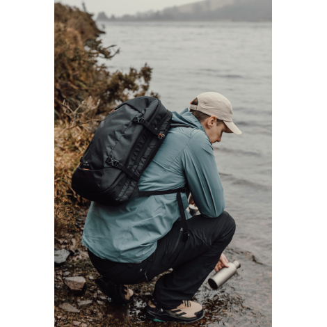 Sac à dos porté par personne accroupie en extérieur, sans personnalisation visible