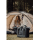 Personne assise devant une tente avec sac isotherme posé à côté sans personnalisation visible