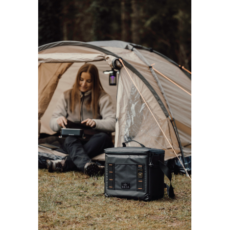 Personne assise devant une tente avec glacière posée à proximité, sans marquage visible