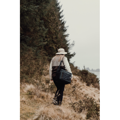 Personne marchant en extérieur avec glacière portée en bandoulière, sans personnalisation visible