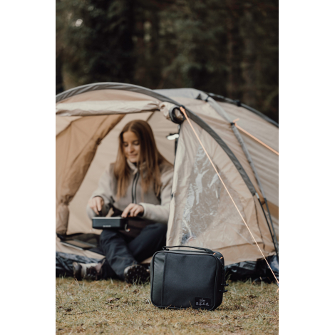 Personne utilisant un lunch bag en extérieur devant une tente sans personnalisation visible