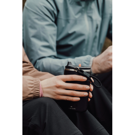 Personne assise tenant un mug isotherme en extérieur sans marquage visible