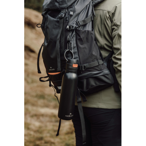 Bouteille accrochée à un sac à dos en extérieur, sans marquage visible