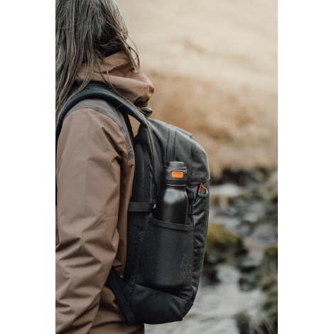 Bouteille rangée dans une poche latérale de sac à dos en extérieur, sans personnalisation visible