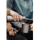 Personne versant une boisson depuis la gourde dans une tasse, sans personnalisation visible Personne versant une boisson depuis la gourde dans une tasse, sans personnalisation visible