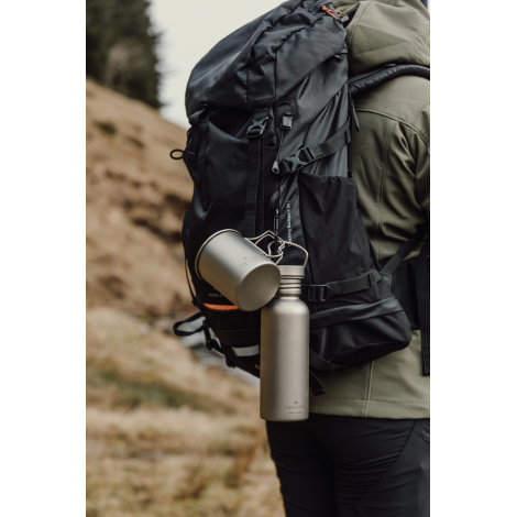 Gourde en titane accrochée à un sac à dos en extérieur, sans personnalisation visible