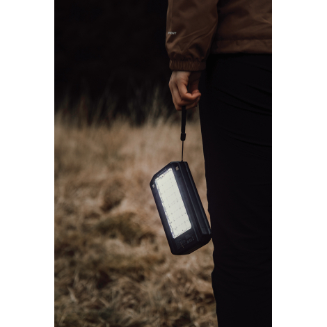 Personne tenant une powerbank allumée à la main en extérieur sans marquage visible