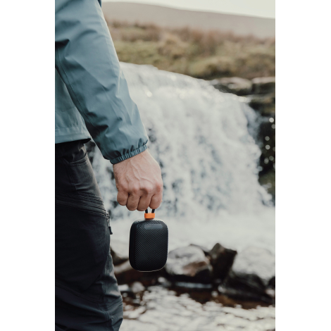 Enceinte tenue à la main près d’une cascade en extérieur sans marquage visible