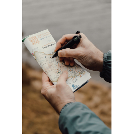 Personne écrivant sur une carte en extérieur avec un crayon infini sans marquage visible