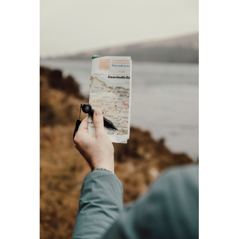 Crayon infini tenu en main au-dessus d’une carte en extérieur sans personnalisation visible