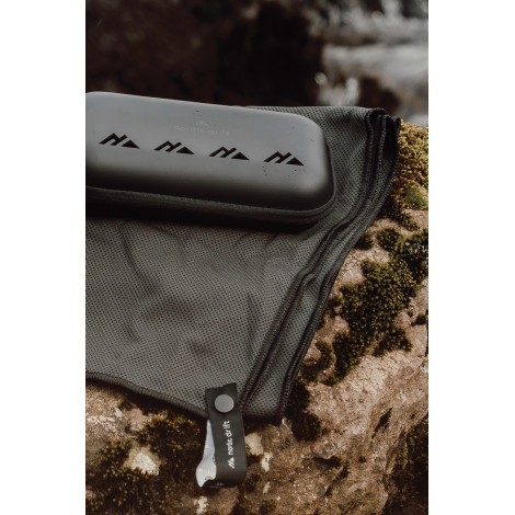 Serviette partiellement rangée dans une housse filet avec étui rigide posé au-dessus sans marquage visible