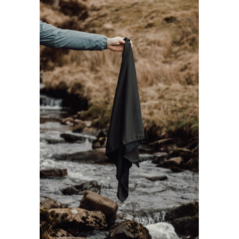 Personne tenant une serviette microfibre au-dessus d’un cours d’eau en extérieur sans personnalisation visible