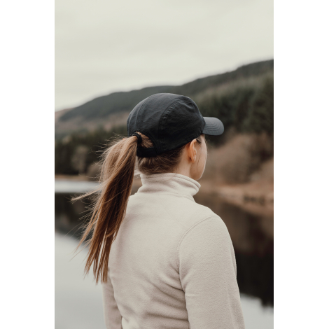 Casquette noire portée par une femme vue de dos en extérieur sans personnalisation visible