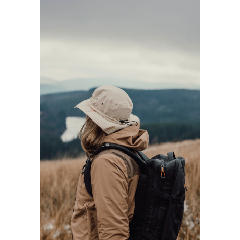 Bob beige porté par une personne de profil en extérieur avec sac à dos sans marquage visible