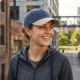 Femme portant la casquette bleue et beige dans un environnement urbain, sans personnalisation visible. Femme portant la casquette bleue et beige dans un environnement urbain, sans personnalisation visible.