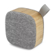 Enceinte sans fil en bambou avec façade en tissu gris et dragonne, sans marquage visible. Enceinte sans fil en bambou avec façade en tissu gris et dragonne, sans marquage visible.