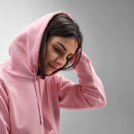 Gros plan d’une femme portant un sweat à capuche rose avec capuche relevée.
