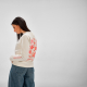 Vue de profil arrière d'une femme portant un sweat femme à col rond écru avec un grand motif personnalisé visible dans le dos et Vue de profil arrière d'une femme portant un sweat femme à col rond écru avec un grand motif personnalisé visible dans le dos et