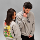Un homme et une femme portent des sweats unisexes gris à col montant zippé. Un marquage est visible sur la poitrine du sweat por Un homme et une femme portent des sweats unisexes gris à col montant zippé. Un marquage est visible sur la poitrine du sweat por