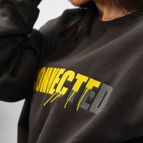 Gros plan sur le devant d'un sweat sombre mettant en évidence une personnalisation visible sur la poitrine ainsi que la texture 