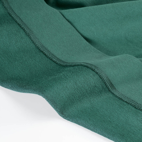 Gros plan de l'intérieur en French Terry d'un sweat vert, mettant en évidence la texture du tissu et le bord-côte inférieur.
