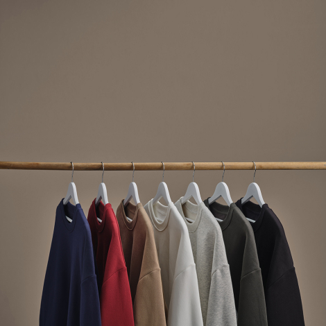 Sept sweats oversize unisexes suspendus sur des cintres, présentés dans différents coloris, sans personnalisation visible.