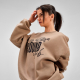 Femme portant un sweat oversize beige avec une grande personnalisation imprimée sur le devant. Femme portant un sweat oversize beige avec une grande personnalisation imprimée sur le devant.