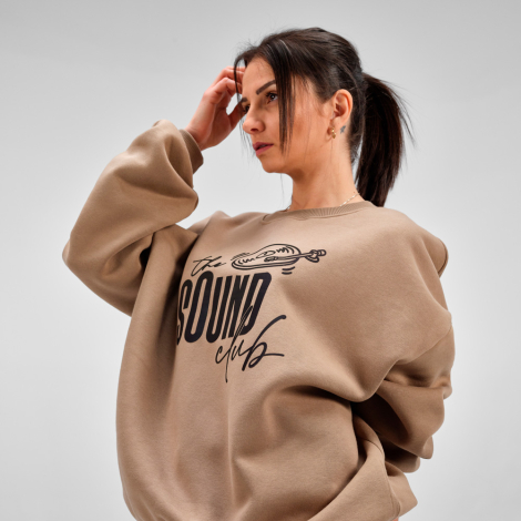 Femme portant un sweat oversize beige avec une grande personnalisation imprimée sur le devant.