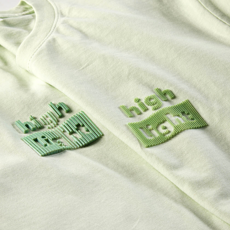 Gros plan comparant deux personnalisations en relief appliquées sur des t-shirts vert pastel au niveau de la poitrine.