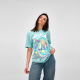Femme portant un t-shirt bleu clair avec une grande personnalisation à effet irisé sur le devant. Femme portant un t-shirt bleu clair avec une grande personnalisation à effet irisé sur le devant.