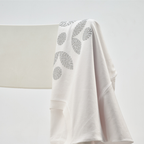 T-shirt blanc suspendu présentant une personnalisation en strass sur la poitrine.