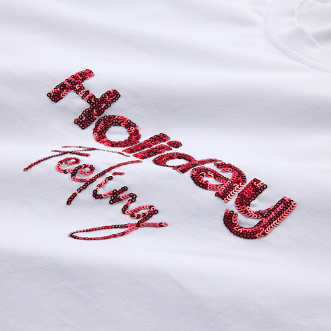 Gros plan d'une personnalisation réalisée en sequins rouges sur un t-shirt blanc.
