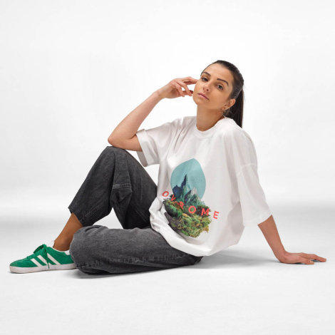 Femme assise portant un t-shirt oversize blanc avec une grande personnalisation graphique imprimée sur le devant.