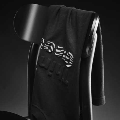 T-shirt noir drapé sur une chaise avec une personnalisation en relief et imprimée visible sur le devant.