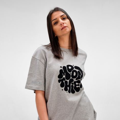 Femme portant un t-shirt oversize gris avec une grande personnalisation imprimée sur le devant et un marquage discret sur la man