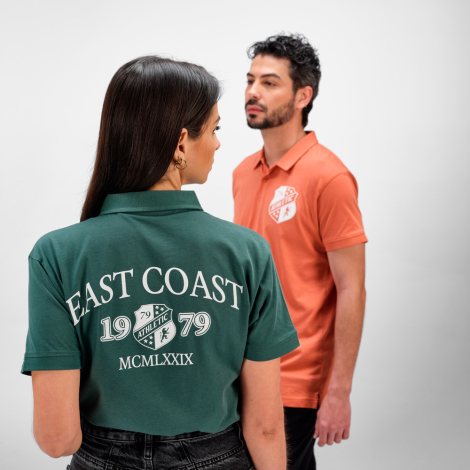 Femme de dos portant un polo vert avec une grande personnalisation imprimée dans le dos, aux côtés d'un homme portant un polo co